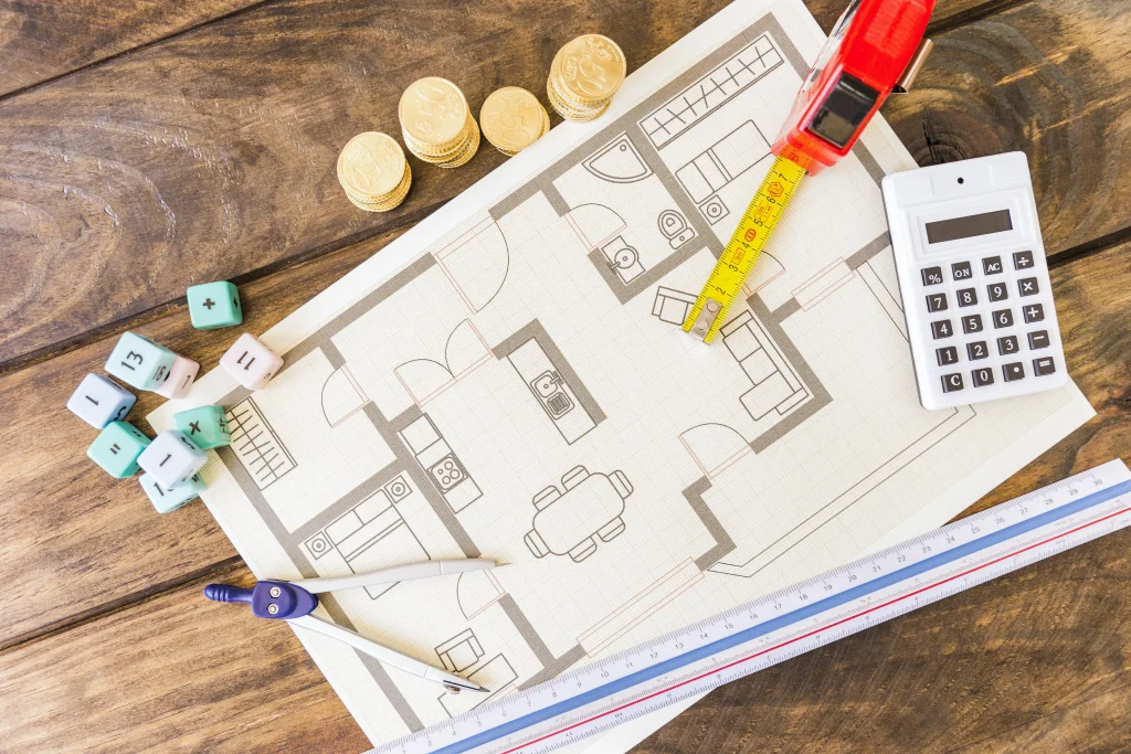 divider-ruler-math-blocks-calculator-stacked-coins-blueprint-wooden-desk-min | Homesell